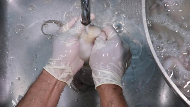 hand mean cleaning and cut  octopus under  tap water.