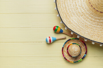 Mexican sombreros and maracas on color wooden background