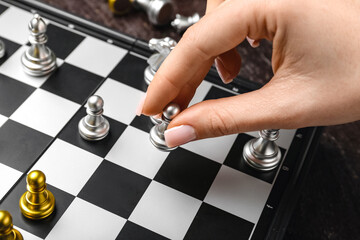 Woman playing chess on dark background, closeup