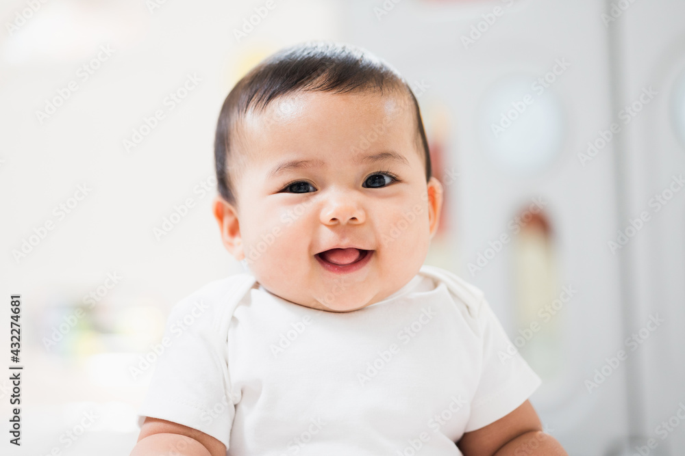 Wall mural A cute baby wearing a white dress Stay with parents in the house