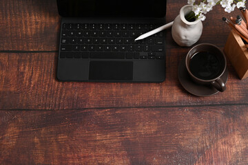 Mock up computer tablet, stylus pen and coffee cup on wooden desk.