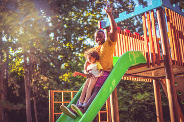 African American father having fun outdoors with his daughter.