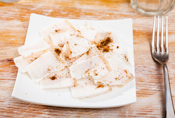 Tender sliced lard on a platter, sprinkled with red pepper seasoning