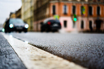 Rainy day in the big city, the cars are driving down the street. Close up view from the level of the dividing line