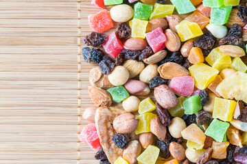 A nutritious mixture of candied fruits, nuts, raisins and dried fruits on a bamboo napkin, top view. Macro photography.