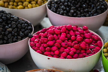 Sales of traditional products.  Mediterranan olives  in the market. Many bowls of black, pink and green olives at the farmer's market