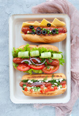 Delicious freshly cooked hot dogs with sausages, vegetables, cheese and sauce top view.