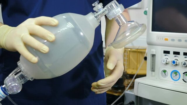 Anesthesiologist with resuscitation breathing bag or Ambu bag in hands. Life saving concept. rescue patients in emergency. Mask for artificial lungs ventilation. Breathing bag with valve inflates and