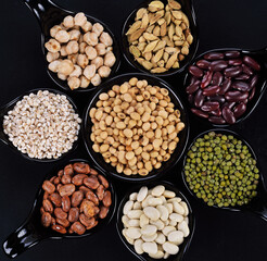 Mix nuts in black bowl on wood background