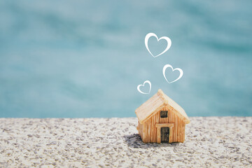miniature house and  heart shape on concrete floor with blurred blue background, copy space, home...