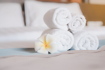 Fototapeta na wymiar hygiene white rolled towel and blooming plumeria flower on cleaned bed in bedroom