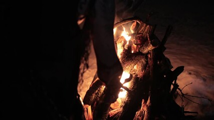 Viking with a torch lights bonfire. Brutal male warrior of dangerous appearance by the fire. The concept of ancient traditions wild life barbarian conquerors.