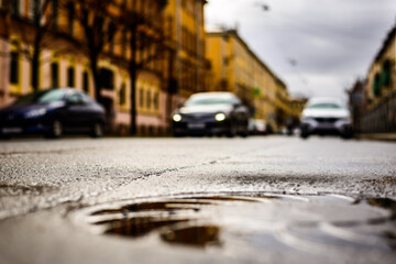 Rainy day in the big city, the headlights of the approaching car. Close up view of a hatch at the level of the asphalt