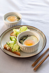 Shirred eggs (Oeuf cocotte) or baked eggs. healthy breakfast with eggs and spinach and toast with cucumber