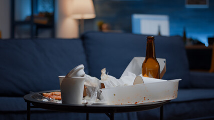 Messy empty living room of depressed person with scattered food mess, disorder table. Unorganized house apartment of alone woman with sever depresion having trash, rubbish with no people in