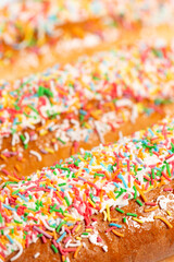 Fototapeta na wymiar Freshly baked iced finger buns with rainbow sprinkles