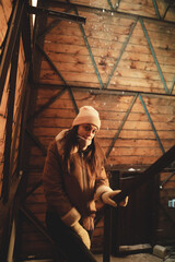 A girl in warm clothes stands inside a village mill