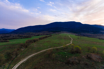 low mountains and pastures in the Carpathian village, landscape at sunset, Ukrainian Carpathians and agricultural fields, trails in the mountains and fields.