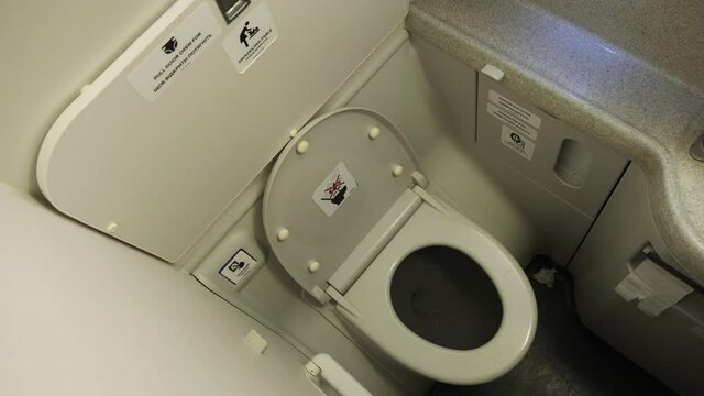 Toilet in the plane. Airplane bathroom. Small, compact, public modern washroom with a white toilet inside the modern aircraft. Inside a toilet onboard in a jet plane. Interior of toilet room.