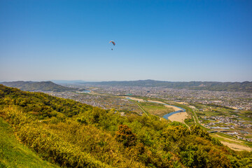 Fototapeta na wymiar 青空の下を飛ぶパラグライダー。紀の川市寺山スカイスポーツにて