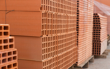 Pallets with stack of redbricks lying at warehouse of building materials in sunny day