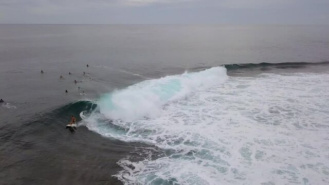 Aerial Shot Of People Surfing In Sea During Sunset, Drone Flying Backward Over Ocean - Siargao, Philippines