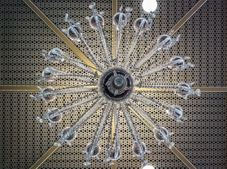 A glassed chandelier on a symmetry ceiling.