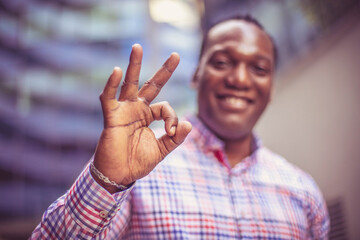 Smiling business man outside, gesturing with hand. Focus on hand.