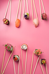 sushi rolls with chopsticks on pink background
