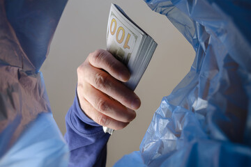 A hand throws money into the trash can.