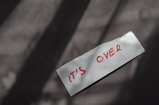 Handwritten note It`s Over on a white piece of paper.