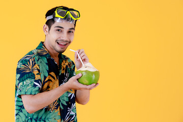Joyful young Asian man holds a fresh young coconut in his hands. Half body studio portrait on...