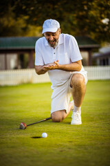 The golfer waits for the ball to enter the hole.