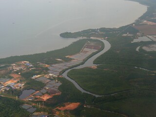 Aerial view approaching Kuala Lumpur with the river merging into the ocean.