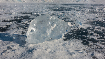 A transparent shining shard of ice. Sun glare on the edges, shadow on the surface of a frozen lake....