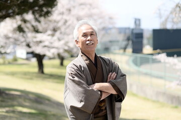 着物を着たシニア男性のポートレートと満開の桜