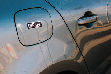 Sticker diesel on a fuel tank door. Rental car concept. Information for tourists renting the vehicle. Blue color reflection of the sky. Copy space. Travel and tourism industry theme