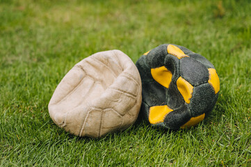 Two lowered football old multi-colored balls lie on the green grass of the sports field. Photo of the match.