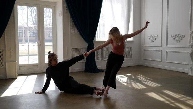 young woman and man are training in dance hall, rehearsing modern dance performance