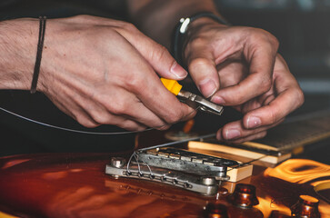 Close up at a person, repairing a guitar