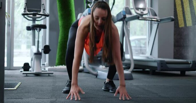 Fitness woman doing burpee workout at gym. Fitness woman strength training doing cardio workout with fast mountain climbers