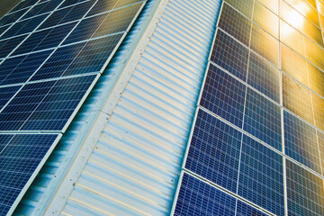 Aerial view of surface of blue photovoltaic solar panels mounted on building roof for producing...