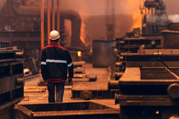 Worker inside Steel metallurgical factory or foundry workshop interior, heavy industry concept.