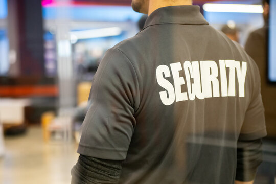 Security guard standing inside commercial building nearby the window reflecting light