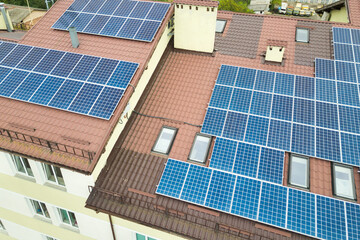 Fototapeta premium Aerial view of solar power plant with blue photovoltaic panels mounted of apartment building roof.