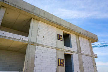 Aerial view of high residential apartment building with storey numbers on wall under construction. Real estate development.