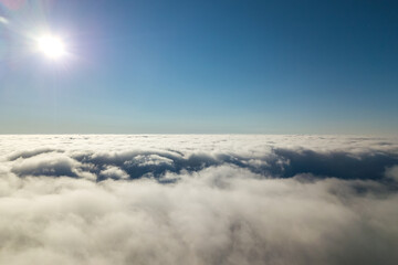 Aerial view from above of white puffy clouds in bright sunny day.