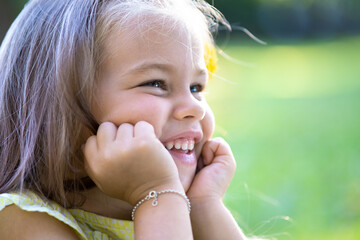 Portrait of happy pretty child girl smiling outdoors enjoying warm sunny summer day.