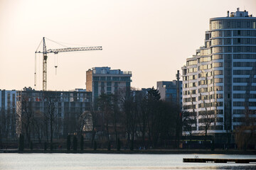 Tower crane and high residential apartment buildings under construction on lake shore. Real estate development.