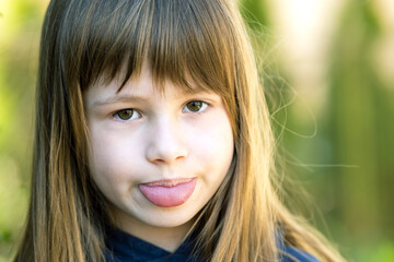 Close up portrait of cute girl showing tongue and looking at camera.